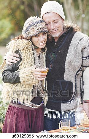 Stock Photography - Portrait of mature hippy couple drinking cider in garden. Fotosearch