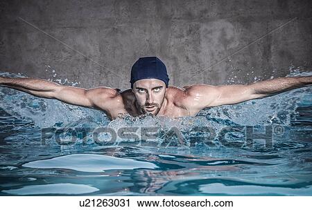 Stock Image - "Portrait of mid adult man doing butterfly stroke in swimming pool, Cagliari, Sardinia, Italy". Fotosearch