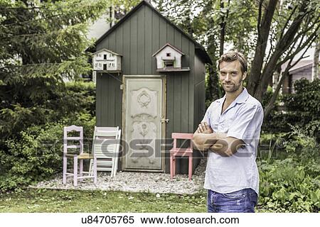 Stock Photography - Portrait of mid adult man in front of garden shed. Fotosearch