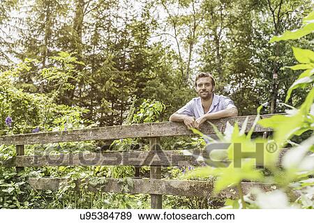 Portrait of mid adult man leaning on garden fence View Large Photo Image Stock Photo - Portrait of mid adult man leaning on garden fence. Fotosearch