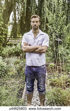 Portrait of mid adult man with arms folded in garden View Large Photo Image Stock Image - Portrait of mid adult man with arms folded in garden. Fotosearch