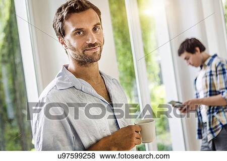 Portrait of mid adult man with coffee cup in sitting room View Large Photo Image Stock Photo - Portrait of mid adult man with coffee cup in sitting room. Fotosearch