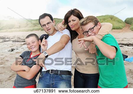 Stock Image - "Portrait of parents and two sons fooling around on beach, Thurlstone, Devon, UK". Fotosearch