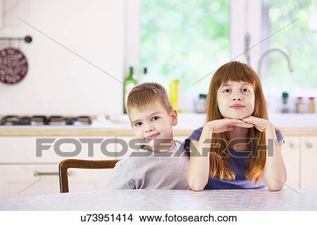Portrait of sister and brother sitting at kitchen table View Large Photo Image Picture - Portrait of sister and brother sitting at kitchen table. Fotosearch