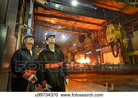 Stock Image - Portrait of steelworkers looking up in forge. Fotosearch