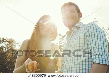 Stock Photo - Portrait of young couple in sunlit in park. Fotosearch