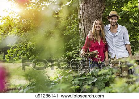 Stock Image - Portrait of young couple with flower basket in garden. Fotosearch