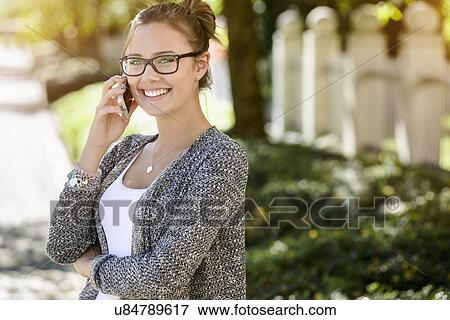 Portrait of young woman in park chatting on smartphone View Large Photo Image Stock Photo - Portrait of young woman in park chatting on smartphone. Fotosearch