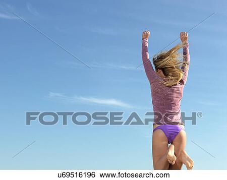 "Rear view of young woman jumping mid air, Altona, Melbourne, Victoria, Australia" View Large Photo Image Stock Photograph - "Rear view of young woman jumping mid air, Altona, Melbourne, Victoria, Australia". Fotosearch
