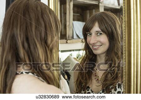 Stock Photo - Reflected portrait of mid adult woman in boutique. Fotosearch