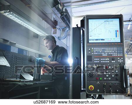 Stock Photo - Reflection of engineer at CNC work station in factory. Fotosearch