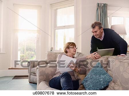 Senior couple at home looking at documents and digital tablet View Large Photo Image Stock Photo - Senior couple at home looking at documents and digital tablet. Fotosearch