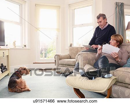 Stock Photograph - Senior couple at home looking at documents and digital tablet. Fotosearch