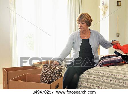 Senior woman in bedroom packing clothes into boxes View Large Photo Image Stock Photo - Senior woman in bedroom packing clothes into boxes. Fotosearch