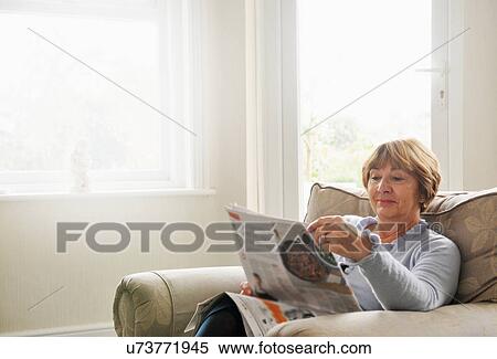 Senior woman sitting in armchair reading magazine View Large Photo Image Stock Photography - Senior woman sitting in armchair reading magazine. Fotosearch
