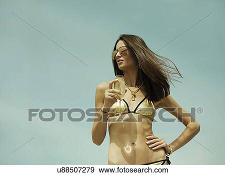 Sexy young woman wearing gold bikini and drinking champagne View Large Photo Image Stock Photo - Sexy young woman wearing gold bikini and drinking champagne. Fotosearch