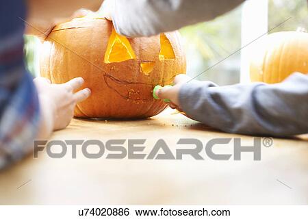 Siblings carving pumpkin in dining room View Large Photo Image Stock Photograph - Siblings carving pumpkin in dining room. Fotosearch