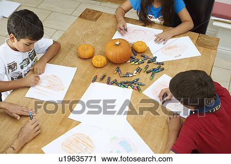 Stock Image - Siblings drawing at dining table. Fotosearch