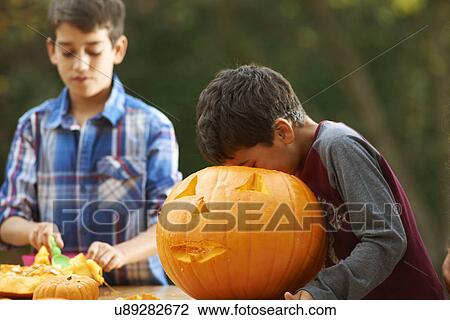 Stock Image - Siblings hollowing out pumpkin. Fotosearch
