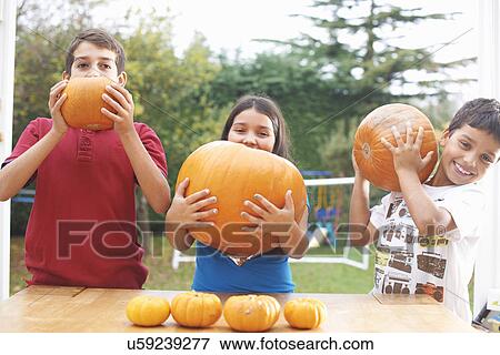 Siblings playing with pumpkin in dining room View Large Photo Image Stock Photo - Siblings playing with pumpkin in dining room. Fotosearch