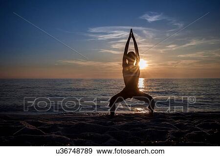 "Silhouetted young woman practicing yoga on beach at sunset, Oristano, Sardinia, Italy" View Large Photo Image Stock Photo - "Silhouetted young woman practicing yoga on beach at sunset, Oristano, Sardinia, Italy". Fotosearch