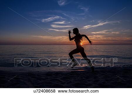"Silhouetted young woman running on sunset beach, Oristano, Sardinia, Italy" View Large Photo Image Stock Photo - "Silhouetted young woman running on sunset beach, Oristano, Sardinia, Italy". Fotosearch