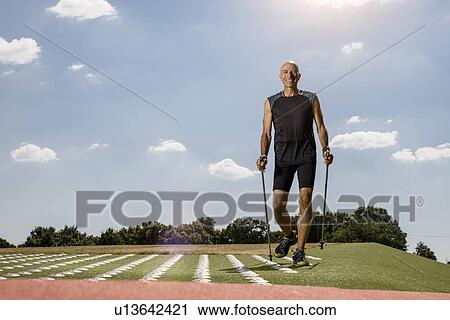 Sportsman walking with hiking pole on field View Large Photo Image Stock Image - Sportsman walking with hiking pole on field. Fotosearch