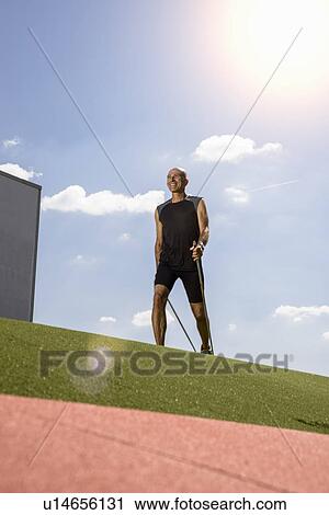 Sportsman walking with hiking pole on field View Large Photo Image Stock Image - Sportsman walking with hiking pole on field. Fotosearch