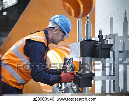 Stock Photograph - Steelworker lifting cutting tool in engineering factory. Fotosearch