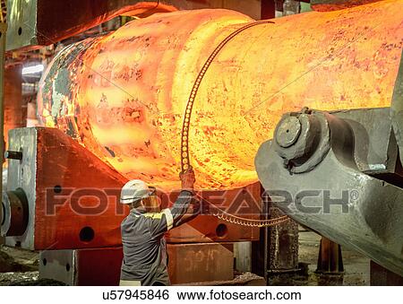 Stock Photograph - Steelworker measuring hot steel casting in forge press. Fotosearch