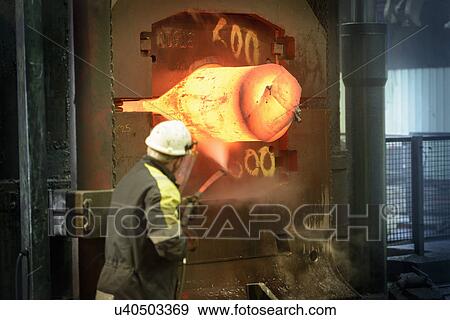 Stock Photo - Steelworker pressure washing forge press. Fotosearch