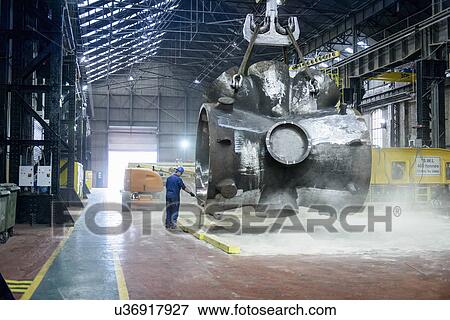 Stock Photo - Steelworker sweeps sand from large casting. Fotosearch