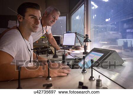 Stock Photo - Steelworkers in control room of forging press. Fotosearch