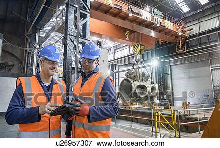 Stock Photo - Steelworkers using digital tablet in engineering factory. Fotosearch
