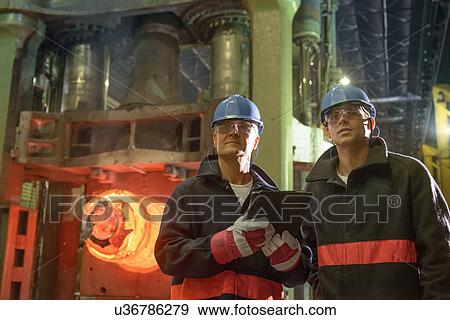 "Steelworkers using digital tablet in front of 10, 000 tonne forging press in steelworks" View Large Photo Image Stock Photo - "Steelworkers using digital tablet in front of 10, 000 tonne forging press in steelworks". Fotosearch