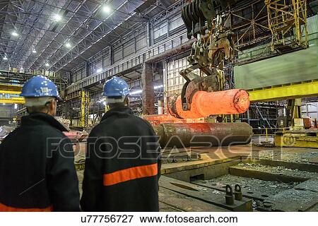 Stock Photo - Steelworkers watching hot steel casting on crane in steelworks. Fotosearch
