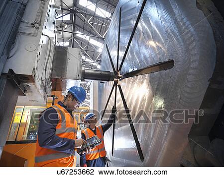Stock Image - Steelworkers with gantry milling machine in engineering factory. Fotosearch