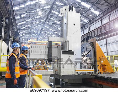 Stock Photo - Steelworkers with gantry milling machine in engineering factory. Fotosearch