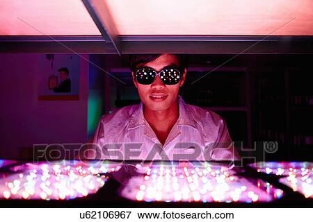 Stock Photo - Technician wearing protective goggles in LED factory. Fotosearch