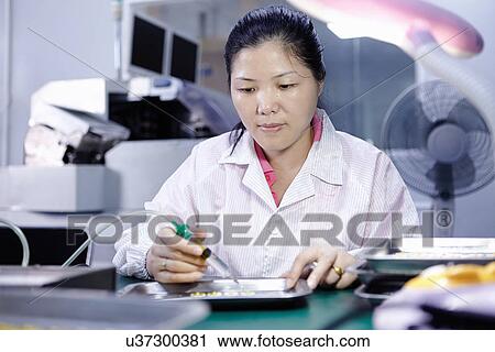 Stock Image - Technician working in LED factory. Fotosearch