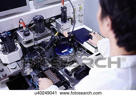 Stock Image - Technician working in LED factory. Fotosearch