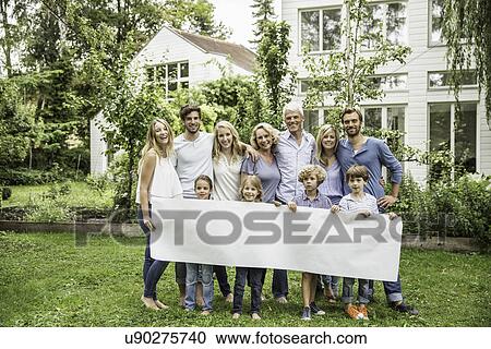 Stock Image - Three generational family in garden with blank banner. Fotosearch