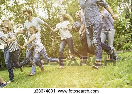 Stock Image - Three generational family running in garden. Fotosearch