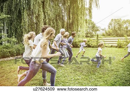 Stock Photo - Three generational family running in garden. Fotosearch