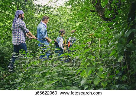 Stock Image - Two adult men and boys dressed up and playing in forest. Fotosearch