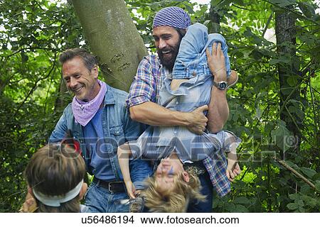 Picture - Two adult men and two boys dressed up and playing in forest. Fotosearch