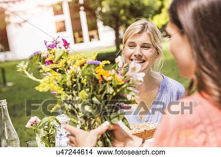 "Two female friends in garden, looking at bunch of flowers" View Large Photo Image Picture - "Two female friends in garden, looking at bunch of flowers". Fotosearch