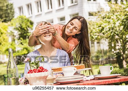 "Two female friends in garden, one coverings the others eyes with hands" View Large Photo Image Stock Photo - "Two female friends in garden, one coverings the others eyes with hands". Fotosearch