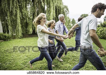 Stock Image - Two generational family running in garden. Fotosearch