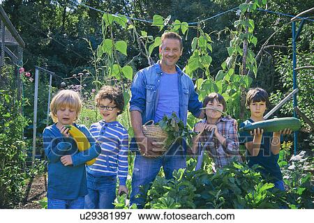 Stock Photo - Two men and sons holding vegetables on allotment. Fotosearch